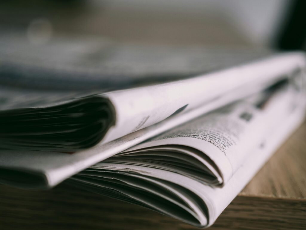Why independent journalism is vital to hold power to account in the Pacific Stack of folded newspapers on a wooden table with a focus on printed pages.