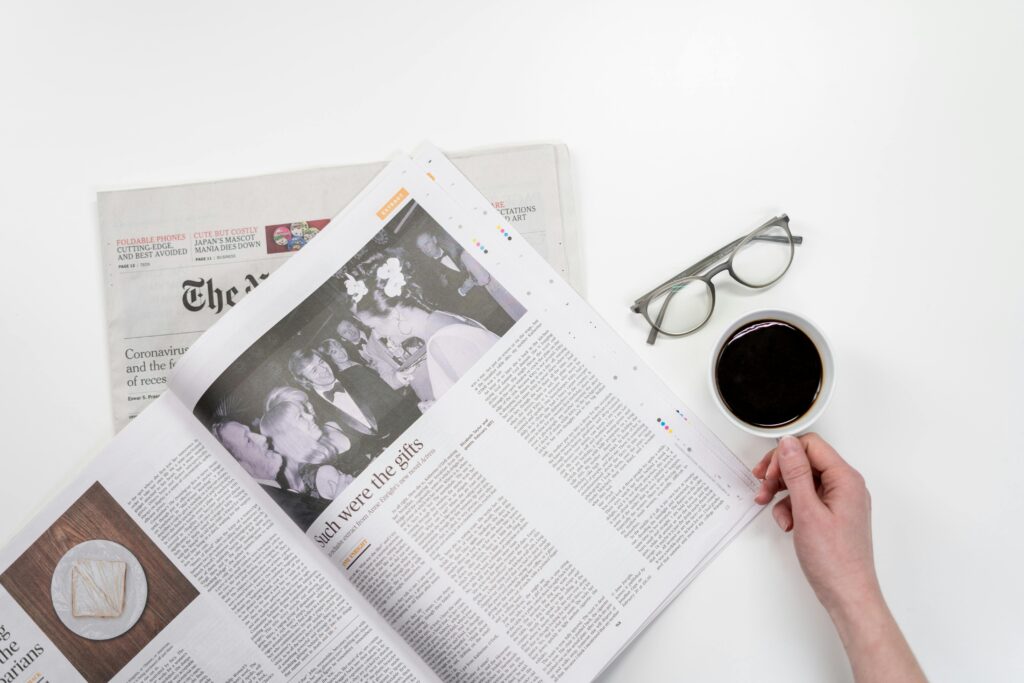Major corruption scandal exposed after documents leaked online Overhead view of newspaper reading with coffee and glasses on a white table.
